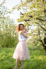 Obraz na płótnie Canvas Young attractive girl walks in spring green park enjoying flowering nature