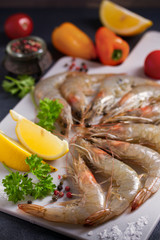 Fototapeta na wymiar Fresh raw prawn shrimps with ingredients for cooking on chopping board. Seafood