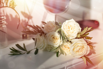 beautiful wedding bouquet of white roses on a light dresser, illuminated by the warm rays of the sun. Background, texture