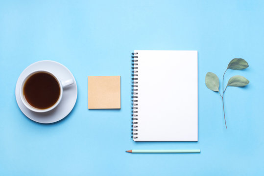 Blue Desk With Cup Of Coffee And Supplies. Flat Lay, Top View.