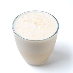 Vanilla milkshake with foam isolated on white. Delicious milk dessert with vanilla in glass...