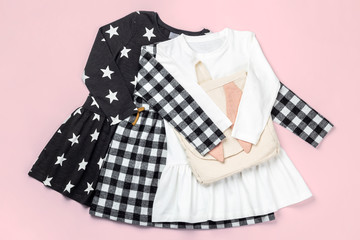 Children fashion. Girl's dresses and bag flat lay on bright pink background.