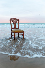 Old chair on the ocean coast, dramatic sky, melancholic scene, loneliness, long exposure