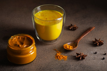 Golden turmeric milk on a dark background star anise cinnamon pepper turmeric paste