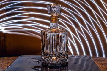 Faceted glass decanter with alcohol. Abstraction on the topic of alcoholism.