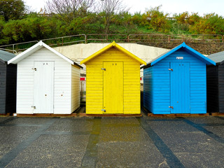 Three beech huts beach huts in primary colours on Lowestoft sea front.