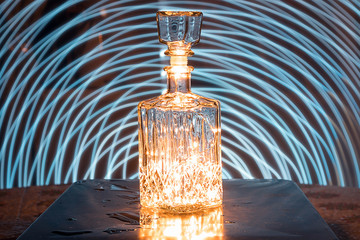 Glass decanter with alcohol. A crystal decanter with garlands inside. Play of light. Drawing with...
