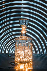 Glass decanter with alcohol. A crystal decanter with garlands inside. Play of light. Drawing with...