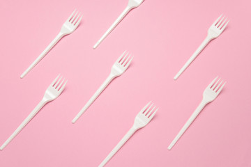 top view white plastic forks pattern on a pastel pink background