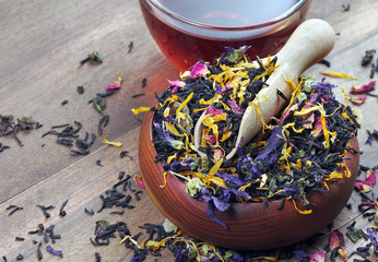 blended tea. black tea with dry flower petals and fruits. dry black tea leaves in a wooden scoop...
