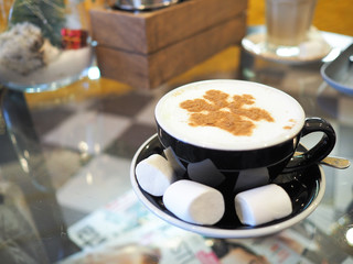 Сoffee latte with a pattern of snowflakes in cup with marshmallow. Warm and cozy winter concept.  