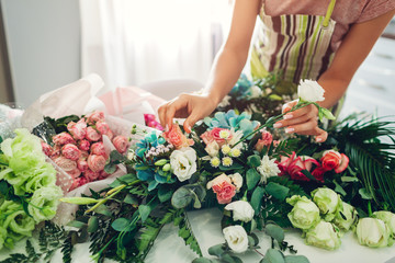 Florist woman creating flower composition at home. Worker composing bouquet for Valentines day. Small business startup