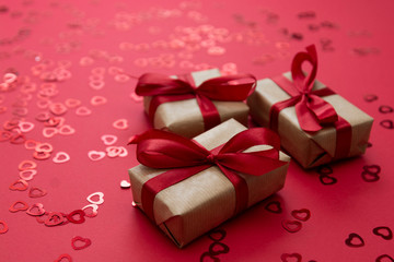 Gift box wrapped with kraft paper and red bow isolated on red background. Abstract flat lay.