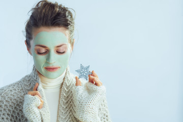elegant housewife with green facial mask showing snowflake