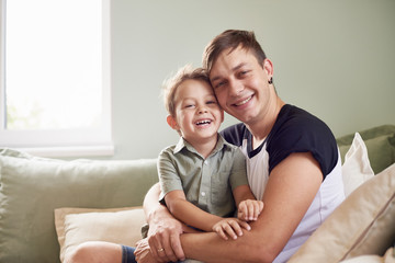 Happy father with his one year old son playing at home on the bed