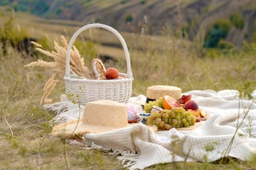 Stylish summer picnic on a white blanket. In a picturesque place the nature of the hills. - obrazy, fototapety, plakaty