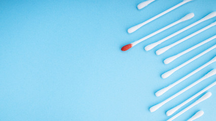 Blood on the hygiene cotton stick. Skincare mockup for design. Menstruation. Stack of disposable cotton stick on a blue background. Cosmetology concept. Bloody wound. Injury. ..