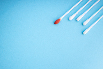 Blood on the hygiene cotton stick. Skincare mockup for design. Menstruation. Stack of disposable cotton stick on a blue background. Cosmetology concept. Bloody wound. Injury. ..