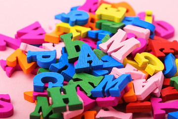 Many multicolored wooden letters on a pink background