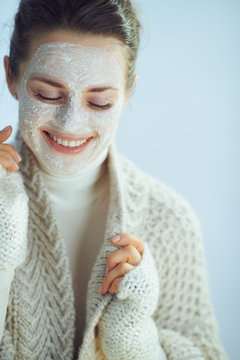 woman with white facial mask on winter light blue background