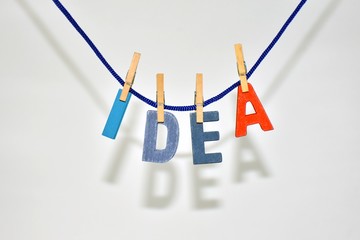 La palabra idea, hecha con letras de madera, colgada en una cuerda con pinzas de la ropa, y la...