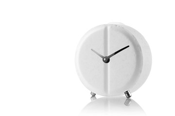 Round white pill in the form of an alarm clock on a mirror surface. Alarm clock - pill on white isolated background.Alarm clock tablet on a white background with place for text, close up