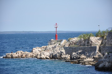 Fototapeta na wymiar Red lighthouse on Croatian rocky coast. Mediterran background.
