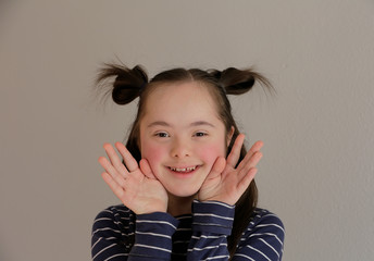 Cute smiling down syndrome girl on the grey background