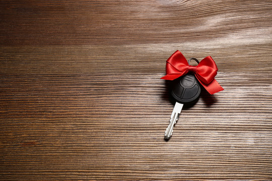 Key With Red Bow And Space For Text On Wooden Background, Top View. Car Buying