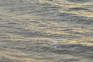  Blurred waving surface of stormy sea water on a sunset with reflection of the sunlight as a natural background.
