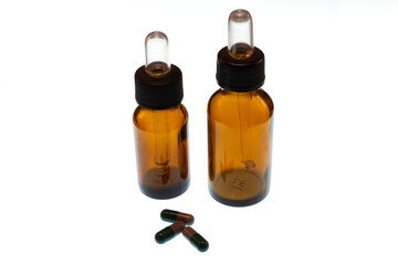Two brown medicinal bottles and some pills with white background
