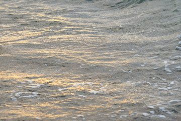  Blurred waving surface of stormy sea water on a sunset with reflection of the sunlight as a natural background.