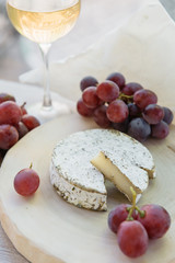 Handmade brie cheese in herbs on wooden table