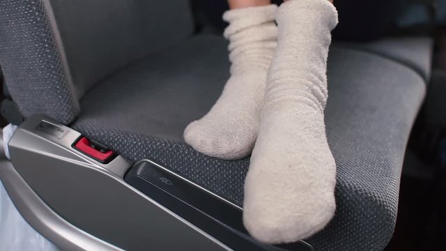 Close-up of legs in white socks lying on the passenger seat of the bus.