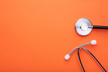 Fototapeta na wymiar Medical stethoscope on orange background. Health care concept