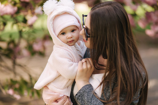 Portrait of mother and her little baby girl. Beautiful mom and cute baby. Mother hud her daughter. Baby dressed in peanch colour hat and smile