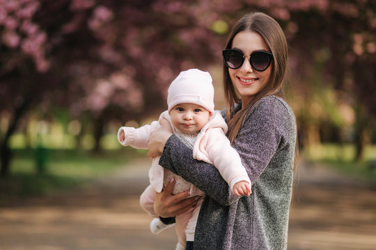Portrait of mother and her little baby girl. Beautiful mom and cute baby. Mother hud her daughter. Baby dressed in peanch colour hat and smile
