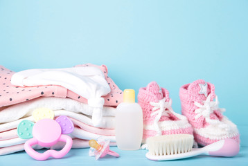 Baby clothes with booties and comb on blue background