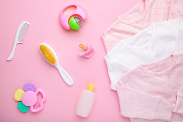 Baby clothes with a shower accessories on a pink background