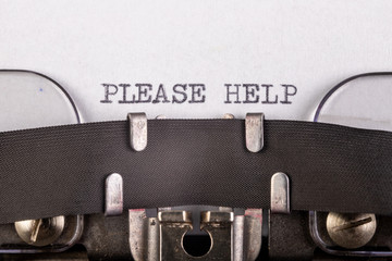 The inscription "please help" on a white sheet of paper in an old typewriter. The old method of printing text.