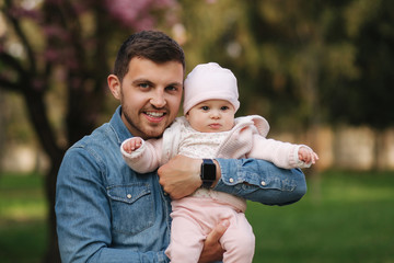 Portrait of beautiful little baby girl on fathers's hands. Happy yound father outside with cute...