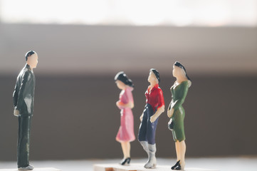 miniature man and women stand on wooden cube confront each other