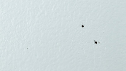 Texture of a white wall with two screw holes