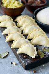 Dumplings with potatoes with herbs on a blue background. Varenyky, vareniki, pierogi, pyrohy - dumplings with filling.