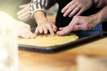 Woman and man teach her friends how to cook food - piza or pie. People cooking at kitchen together. Culinary master class