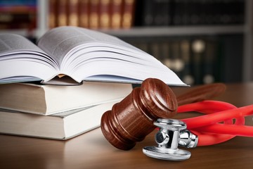Open book on a stack of books with stethoscope and library background.