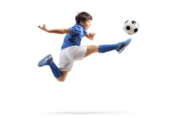 Boy in a sports jersey jumping and kicking a soccer ball