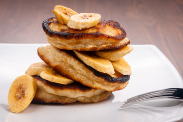 Pancakes with banana on a wooden background
