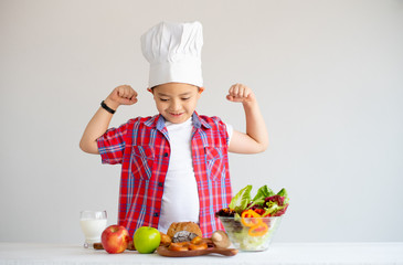 Asian red shirt little boy show action of feel stronger with various types of vegetable and fruits with healthy food concept for children.