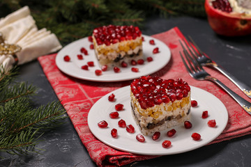 Festive salad in layers in the shape of a heart, decorated with pomegranate seeds on a dark background, Horizontal orientation